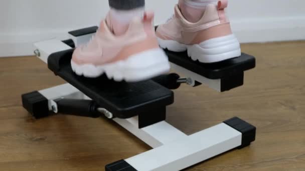 Primer plano pie de mujer haciendo ejercicio en la máquina de ejercicio stepper en el gimnasio, máquina stepper en el piso de madera . — Vídeo de stock