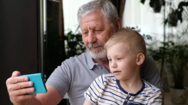 Çocuk, dedesi Senoir ile birlikte akıllı telefondan selfie çekiyor.