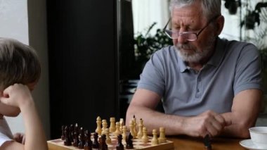 Küçük çocuk büyükbabasıyla satranç oynuyor, kıdemli pozitif adam.