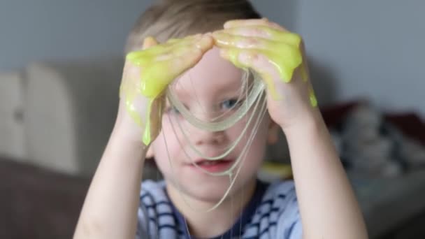 Leuke jongen die met lichtgroen slijm speelt. Sluiten. — Stockvideo