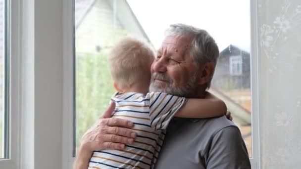 Маленький хлопчик обіймає свого дідуся вдома, старший позитивний чоловік — стокове відео