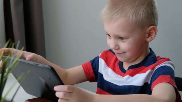 Lindo niño de escuela aprendiendo o jugando en la computadora tableta PC, concepto de educación a distancia . — Vídeos de Stock