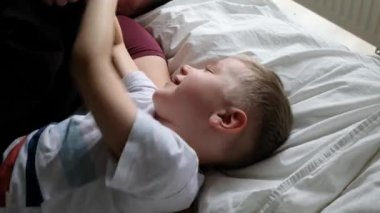 Mutlu baba oğluyla yatakta eğleniyor, gülüyor. Yukarıdan görüntüle