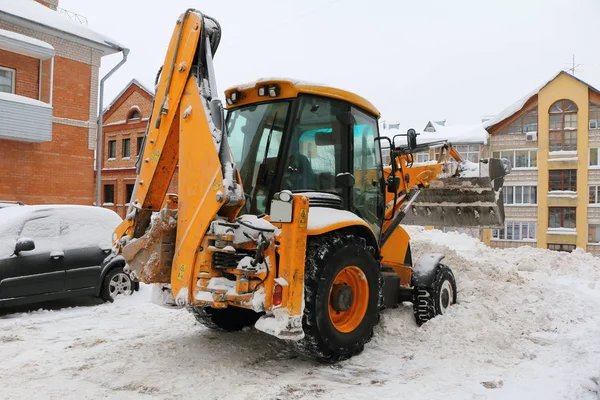 Traktor in der Stadt reinigt Hof vom Schnee. — Stockfoto