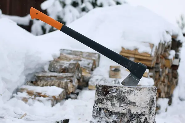 Woodpile karla kaplı arka planda yakacak odun doğrama için axe olduğunu. — Stok fotoğraf