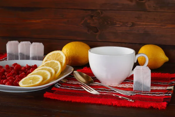 Tea accessories, lemons, dried cherries are on a dark wooden background.