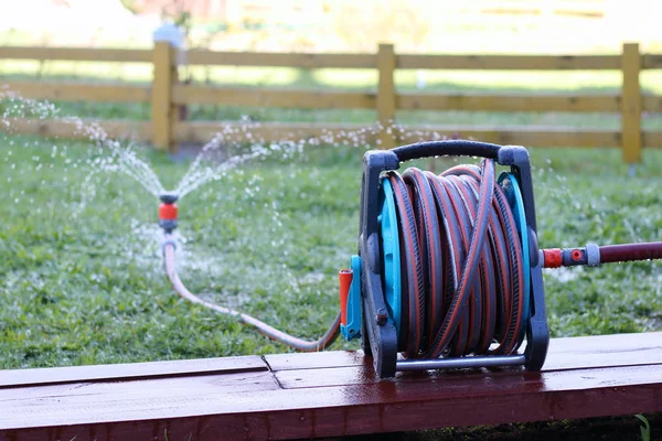 Slangupprullare med slang och sprinkler finns i trädgården. — Stockfoto