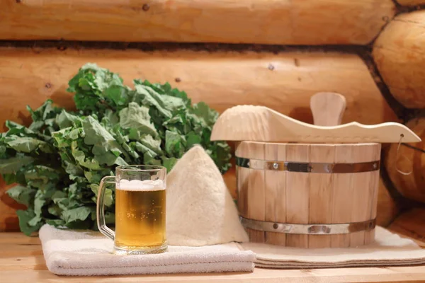 A mug of light beer and bath accessories are in the interior of the Russian bath.