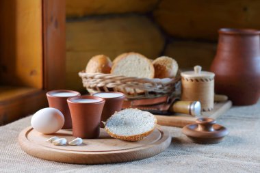 Bardak süt ve ekmek ile bir hasır sepet. 