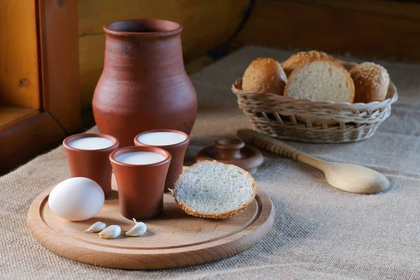 Copas con leche y una cesta de mimbre con pan . — Foto de Stock