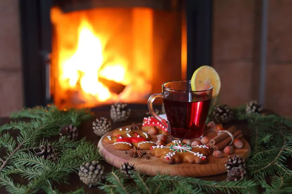 Mulled şarap. Bir kupa ile gingerbread çerezleri şöminenin önünde köknar dallar arasında ahşap bir masa üzerinde mulled şarap.