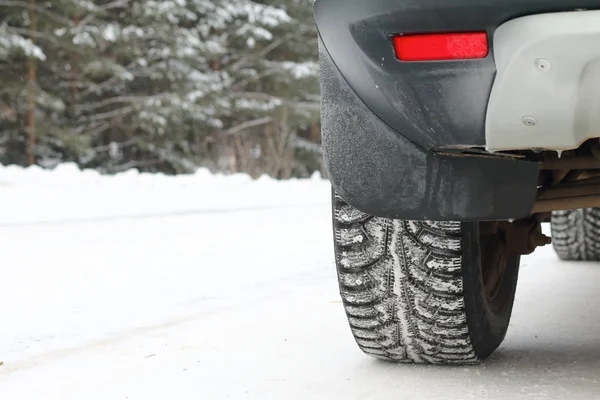 A car is standing by the side of the road in the winter forest. Winter tires.