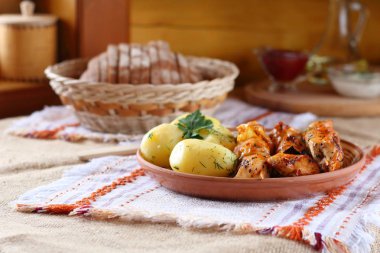 Haşlanmış patates ile tavuk şiş. Kızarmış tavuk şiş ve haşlanmış patates yeşillik bir seramik tabak parçaları.