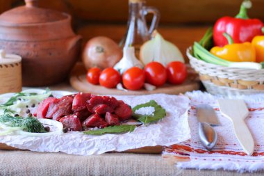 Parşömen kağıt sebzeler, otlar ve baharatlar arasında soğutulmuş çiğ et parçaları.