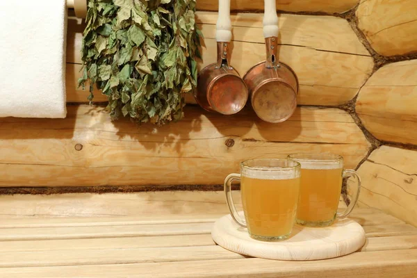 銅製のアクセサリーの間でサウナの内部に軽いビールの2つのガラスマグカップ — ストック写真