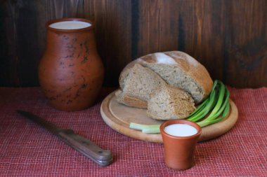 Ahşap zeminde bir bardak kil süt ve bir somun ekmek.. 