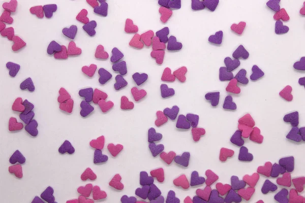 This is a photograph of Pink and Purple heart sprinkles isolated on a White background