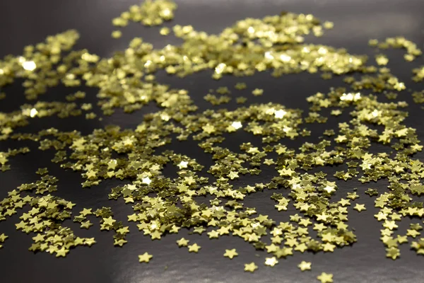 This is a photograph of Gold star sequins placed on a Black background
