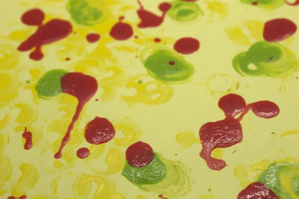 This is a photograph of Red,Green and Yellow nail polish splattered onto a Yellow paper