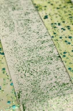 Bu, açık yeşil parıltılı boya ve yıldız pulları kullanarak oluşturulan çizgilerin düzenlenmesiyle oluşan soyut bir arkaplan fotoğrafı.