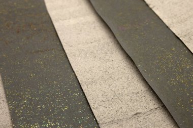 Bu, akrilik boya, altın ve bronz parıltı kullanarak yaratılmış parlak desenli siyah ve bej çizgili bir arkaplan fotoğrafı.