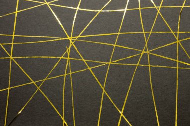 Bu, siyah bir kağıda uygulanan altın bantla yaratılmış geometrik bir tasarımın fotoğrafı.