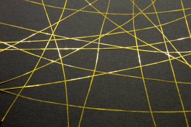 Bu, siyah bir kağıda uygulanan altın bantla yaratılmış geometrik bir tasarımın fotoğrafı.