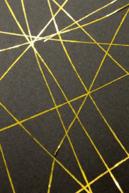 Bu, siyah bir kağıda uygulanan altın bantla yaratılmış geometrik bir tasarımın fotoğrafı.