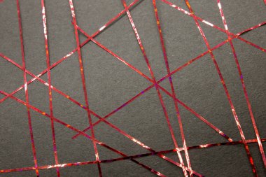 Bu, siyah bir kağıda uygulanan kırmızı bant kullanılarak yapılmış geometrik bir tasarımın fotoğrafı.