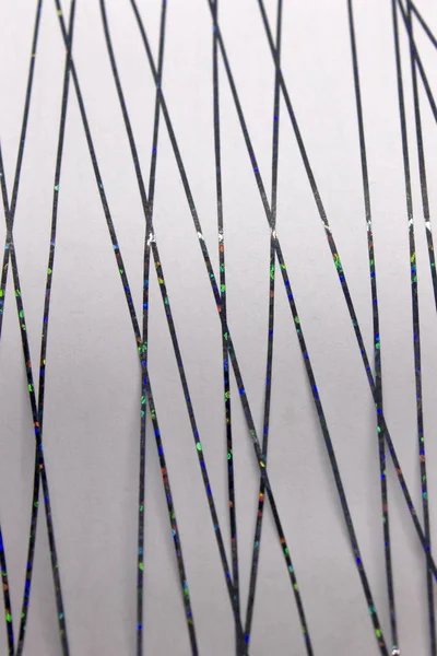 Bu, siyah metalik bantla oluşturulmuş soyut geometrik bir tasarımın Beyaz kağıda uygulanan bir fotoğrafı.