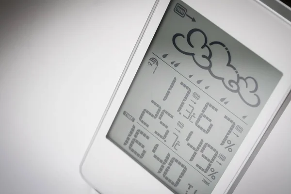 Weather station device with weather conditions inside and outside. Light background.