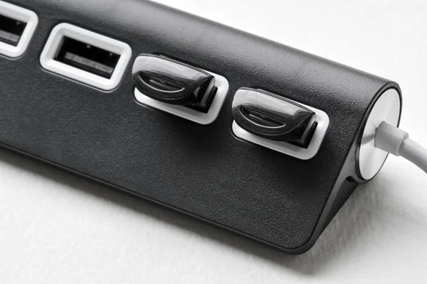 Hub USB portable noir pour quatre connexions avec des lecteurs flash USB sur un fond blanc. Bus appauvri. Gros plan, foyer sélectif — Photo