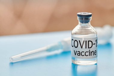 Kavramsal görüntü. Covid-19 'dan korumak için aşı şişesi ve şırıngalar. Yakın plan, mavi arka plan. Sağlık ve Tıp Konsepti.