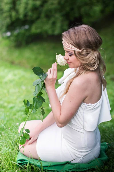 Schönes Mädchen schnüffelt weiße Rose — Stockfoto