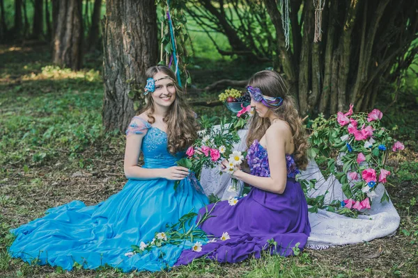 two adult sisters are twins with flowers in the summer garden