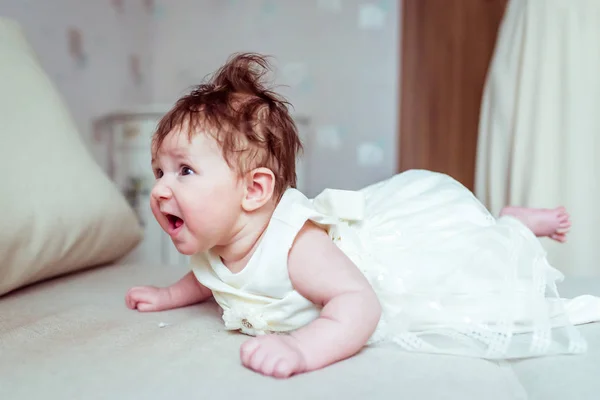 ベッドに横になっている白いドレスの赤ちゃん — ストック写真
