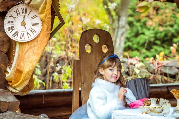 Uma menina bonita segurando chapéu de cilindro com orelhas como um coelho nas mãos na mesa — Fotografia de Stock