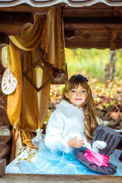 Una niña hermosa sosteniendo el sombrero del cilindro con orejas como un conejo en las manos en la mesa —  Fotos de Stock