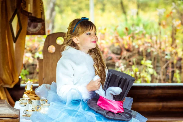 Una niña hermosa sosteniendo el sombrero del cilindro con orejas como un conejo en las manos en la mesa —  Fotos de Stock