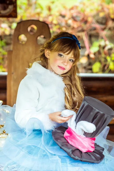 Una niña hermosa sosteniendo el sombrero del cilindro con orejas como un conejo en las manos en la mesa —  Fotos de Stock