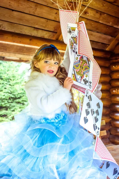 Una niña hermosa jugando y bailando con grandes naipes sobre la mesa —  Fotos de Stock