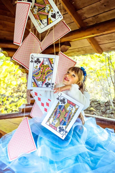 Uma menina bonita brincando e dançando com grandes cartas de baralho na mesa — Fotografia de Stock