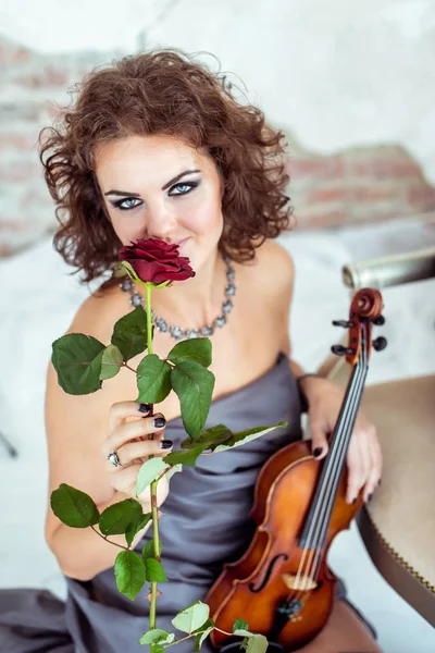 Bella donna in possesso di un violino e odore di rosa rossa — Foto Stock
