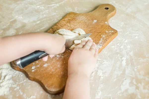 Дитячі руки ріжуть сире тісто — стокове фото