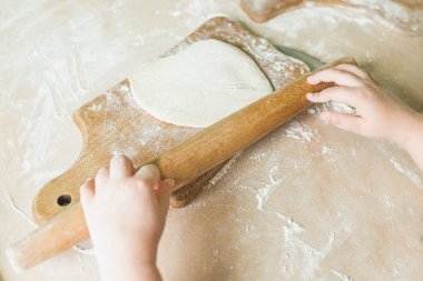 Bir çocuk çiğ hamur rulo