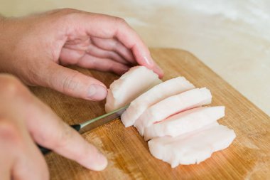 bir adam pişmemiş domuz yağı parçalar halinde keser.