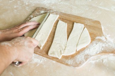 Bir adam hamur parçalar halinde keser.