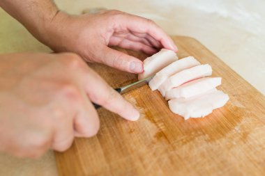 bir adam pişmemiş domuz yağı parçalar halinde keser.