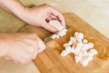 bir adam pişmemiş domuz yağı parçalar halinde keser.