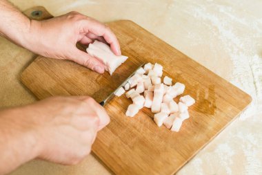 bir adam pişmemiş domuz yağı parçalar halinde keser.